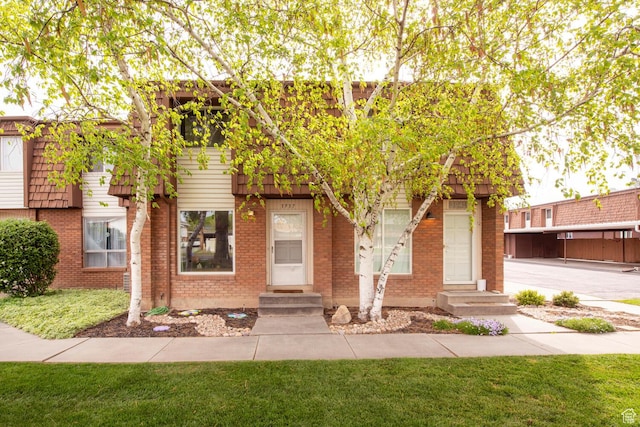 view of front facade featuring a front lawn, entry steps, and brick siding