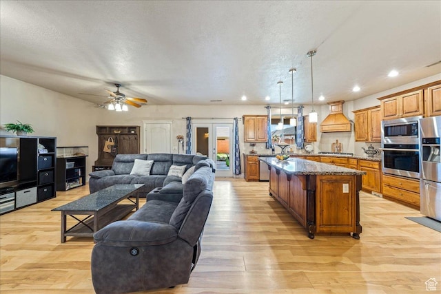 388 E 1060 S, Ivins, UT 84738 - kitchen featuring light wood-style flooring, custom range hood, stainless steel appliances, a center island, and open floor plan