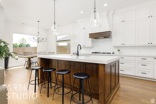 309 W Blue Quartz Dr, Washington, UT 84780 - kitchen with a sink, light wood-type flooring, tasteful backsplash, light countertops, and premium range hood