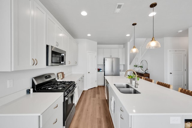 315 W 910 S, American Fork, UT 84003 - kitchen with stainless steel appliances, light wood finished floors, a sink, white cabinetry, and visible vents