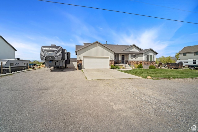 9457 N 4800 W, Elwood, UT 84337 - view of front of home featuring a garage, a front lawn, driveway, and stone siding