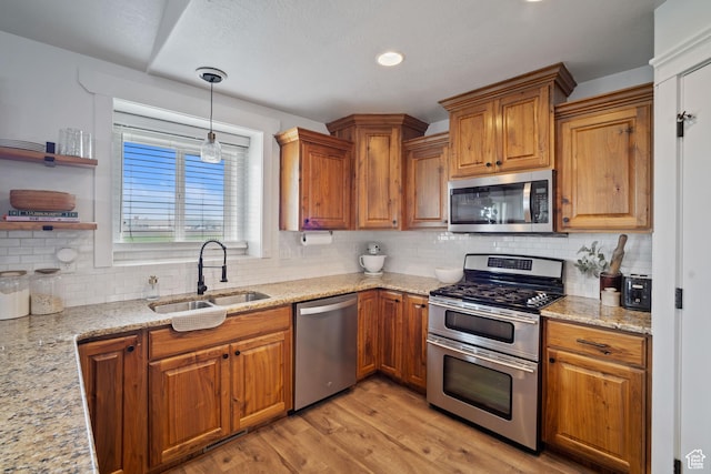9457 N 4800 W, Elwood, UT 84337 - kitchen featuring a sink, light wood-style floors, stainless steel appliances, brown cabinetry, and backsplash