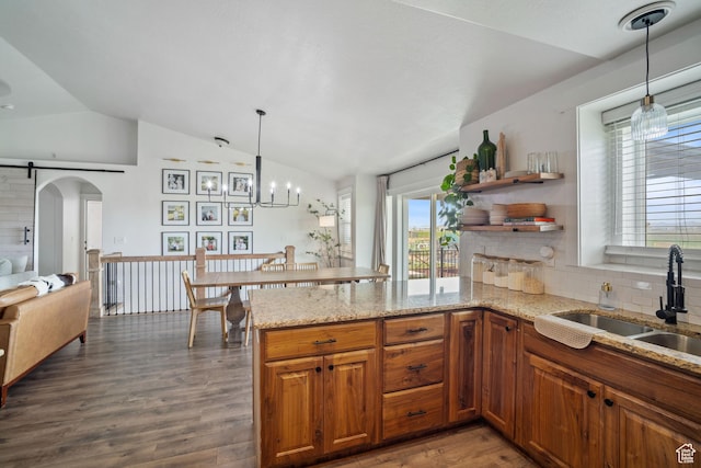 9457 N 4800 W, Elwood, UT 84337 - kitchen featuring wood finished floors, vaulted ceiling, brown cabinets, a sink, and a peninsula
