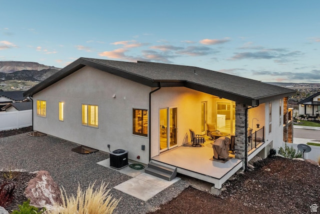 6593 W Bonnie Jean Ln Unit 13, Herriman, UT 84096 - back of house at dusk with stucco siding, fence, cooling unit, and a deck with mountain view