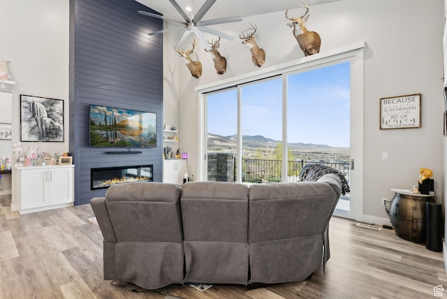 6593 W Bonnie Jean Ln Unit 13, Herriman, UT 84096 - living room featuring a fireplace, light wood-style floors, a ceiling fan, baseboards, and a towering ceiling