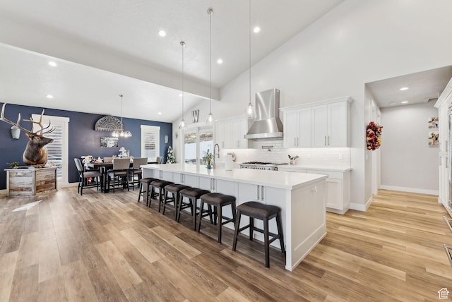 6593 W Bonnie Jean Ln Unit 13, Herriman, UT 84096 - kitchen featuring wall chimney exhaust hood, a breakfast bar, light wood-style flooring, and light countertops