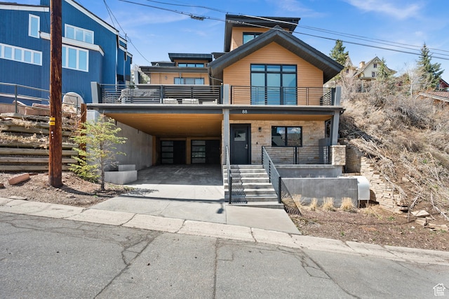 view of front of property featuring concrete driveway, a carport, covered porch, and a balcony