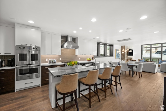 88 King Rd, Park City, UT 84060 - kitchen with modern cabinets, a kitchen bar, wall chimney exhaust hood, a sink, and appliances with stainless steel finishes