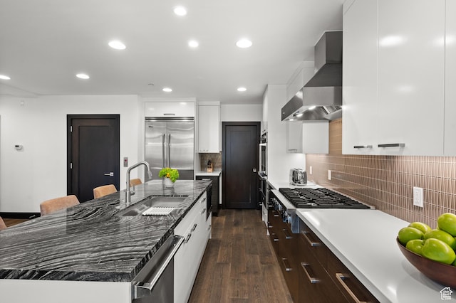 88 King Rd, Park City, UT 84060 - kitchen featuring wall chimney range hood, a kitchen island with sink, dark wood-style flooring, appliances with stainless steel finishes, and a sink