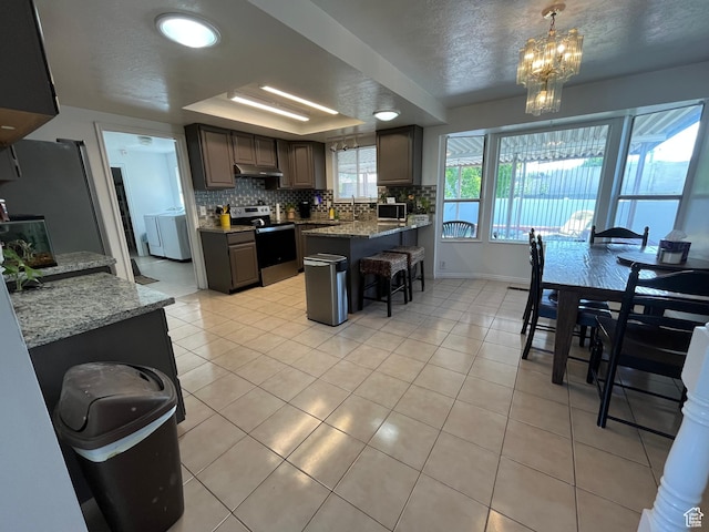 4616 S 3720 W, West Valley City, UT 84120 - kitchen featuring a breakfast bar area, backsplash, a peninsula, under cabinet range hood, and stainless steel appliances