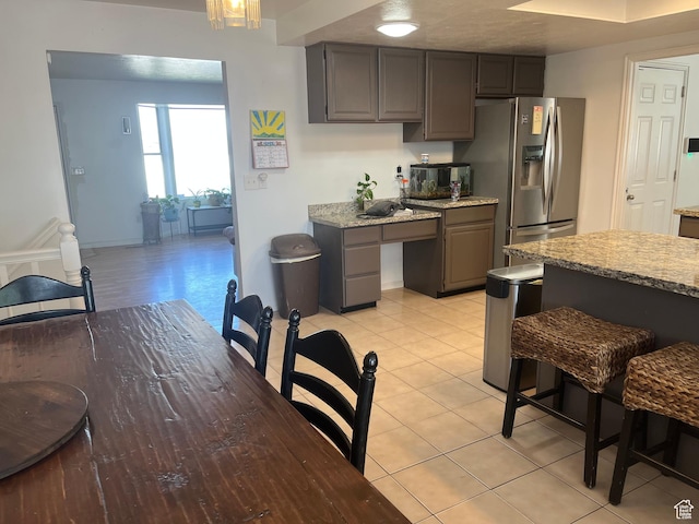 4616 S 3720 W, West Valley City, UT 84120 - kitchen featuring gray cabinets, light stone countertops, light tile patterned floors, baseboards, and stainless steel fridge