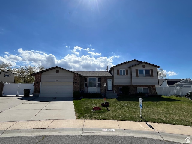 4616 S 3720 W, West Valley City, UT 84120 - tri-level home featuring a front lawn, fence, brick siding, concrete driveway, and an attached garage