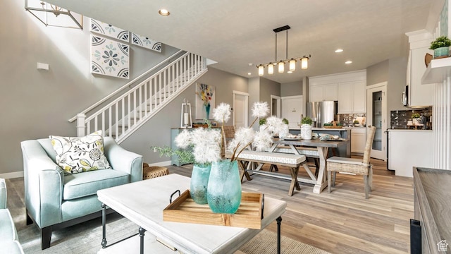 living area with recessed lighting, stairway, light wood-style flooring, and baseboards