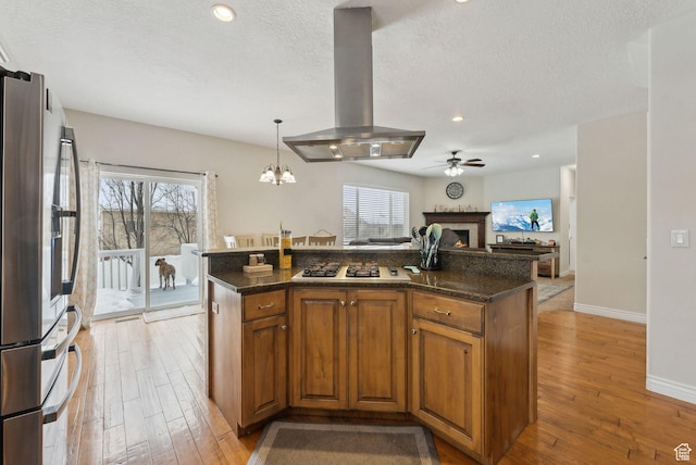 53 W 300 S, Midway, UT 84049 - kitchen featuring light wood-type flooring, island exhaust hood, appliances with stainless steel finishes, and a warm lit fireplace