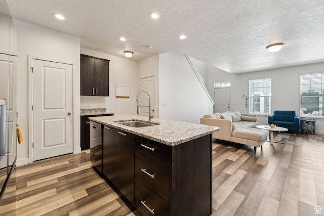 kitchen with dark brown cabinets, a textured ceiling, a sink, and wood finished floors