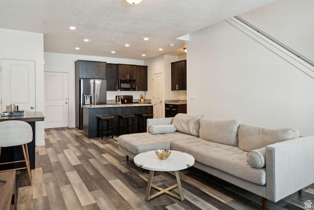 living room featuring recessed lighting, a textured ceiling, and wood finished floors