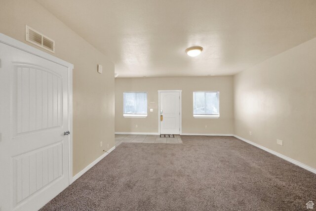 unfurnished room with carpet flooring, visible vents, and baseboards