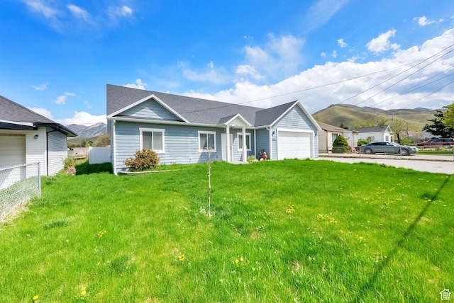 ranch-style home featuring a mountain view, a front yard, an attached garage, and fence
