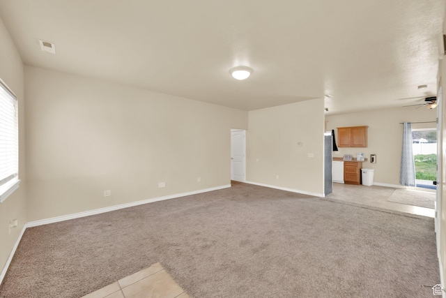 unfurnished living room with ceiling fan, baseboards, light colored carpet, and plenty of natural light