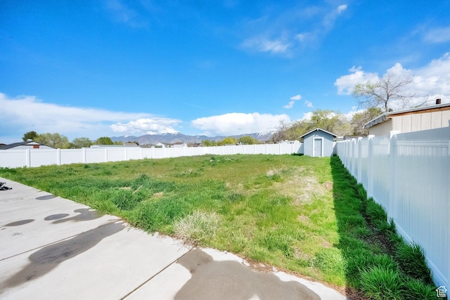 view of yard featuring a storage unit, an outbuilding, and a fenced backyard