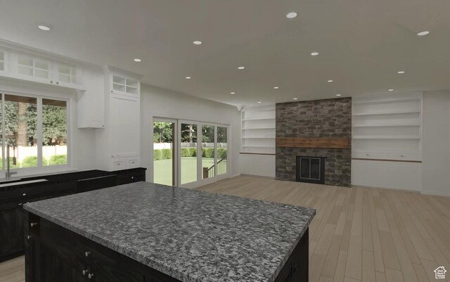 kitchen featuring a wealth of natural light, light wood-style floors, built in shelves, dark cabinetry, and a center island