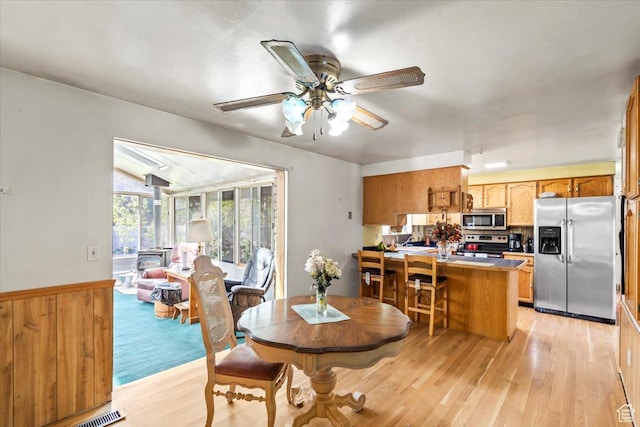 dining room with vaulted ceiling, ceiling fan, light wood-style flooring, and visible vents