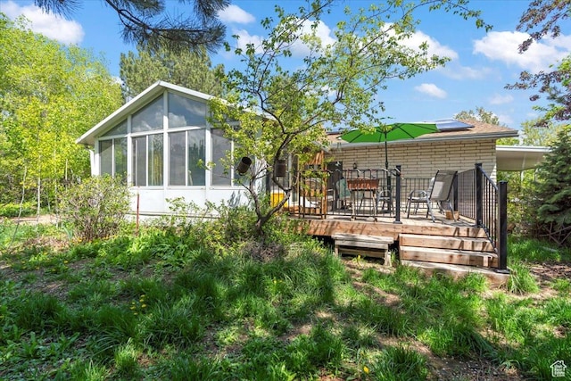 back of property featuring a deck, a sunroom, and outdoor dining area