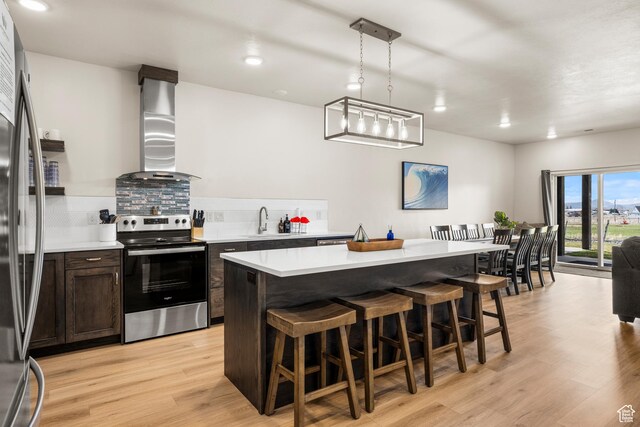 140 W 150 S Unit H29, Garden City, UT 84028 - kitchen with a breakfast bar area, appliances with stainless steel finishes, wall chimney range hood, and light countertops