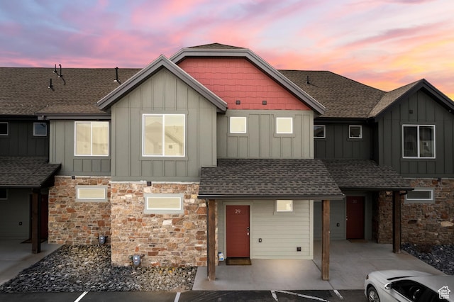 view of front of property with board and batten siding, a shingled roof, and stone siding