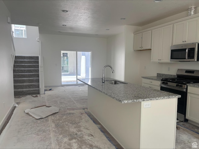 kitchen featuring light stone counters, a sink, a healthy amount of sunlight, and stainless steel appliances