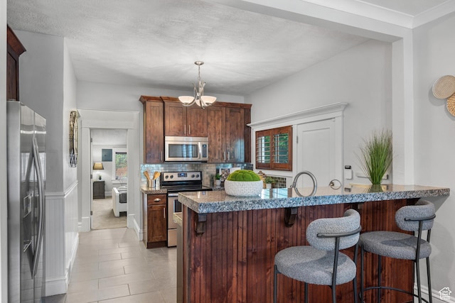 447 E Westminster Ave S, Salt Lake City, UT 84115 - kitchen featuring stainless steel appliances, a breakfast bar area, a chandelier, backsplash, and a textured ceiling