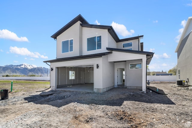 view of front of house featuring stucco siding, a garage, a patio, central AC unit, and a mountain view