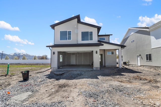 1232 W 575 S, Logan, UT 84321 - view of front of home featuring dirt driveway, a mountain view, fence, central AC unit, and a garage
