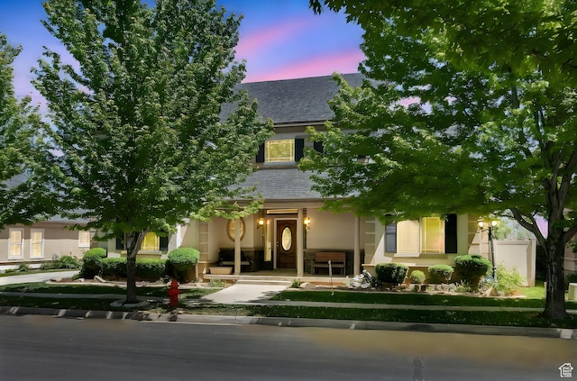 6861 S Triumph Ln, West Jordan, UT 84084 - view of property hidden behind natural elements featuring stucco siding, roof with shingles, and a porch