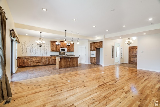 1059 S Ridge Rd, Cedar City, UT 84720 - kitchen with recessed lighting, white appliances, brown cabinetry, light wood-type flooring, and a notable chandelier
