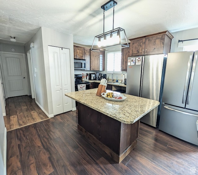 4635 W Eskesen Dr S, West Valley City, UT 84120 - kitchen featuring light stone counters, stainless steel appliances, a kitchen island, dark wood-style flooring, and pendant lighting