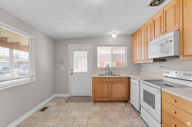 kitchen featuring visible vents, white appliances, light countertops, and a sink