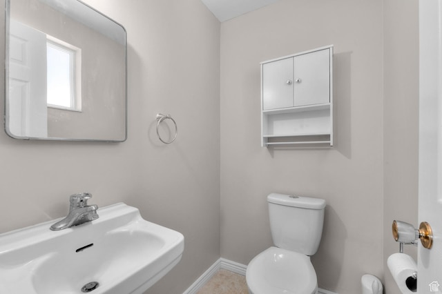 bathroom with toilet, a sink, and baseboards