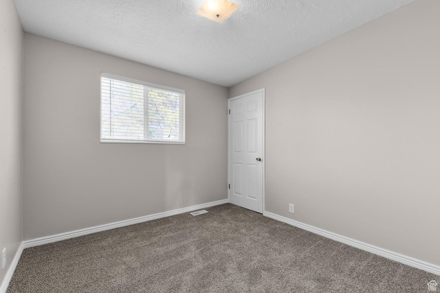 carpeted empty room featuring a textured ceiling, visible vents, and baseboards