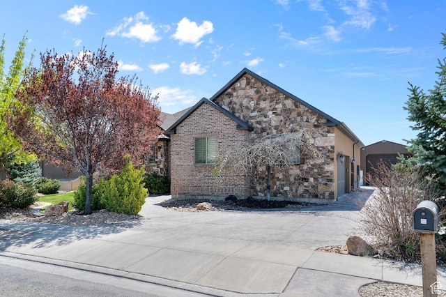 view of home's exterior with concrete driveway, brick siding, an attached garage, and stone siding