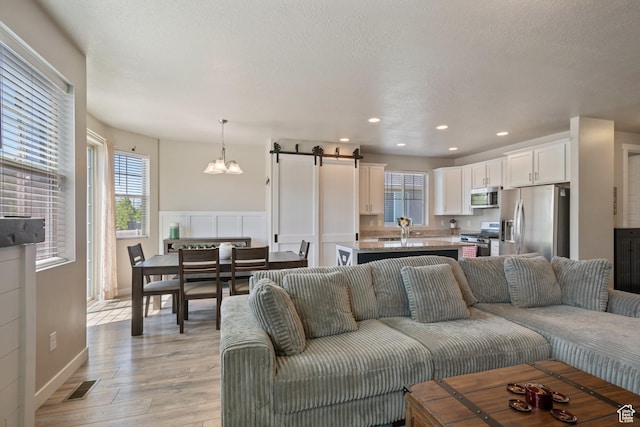 1013 W 90 S, Spanish Fork, UT 84660 - living room featuring a chandelier, light wood-style flooring, a barn door, and recessed lighting