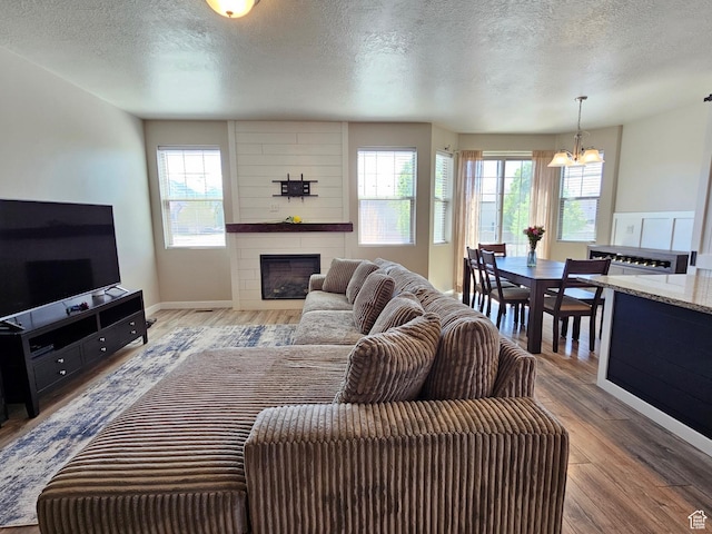 1013 W 90 S, Spanish Fork, UT 84660 - living area featuring a textured ceiling, a chandelier, a fireplace, healthy amount of natural light, and wood finished floors