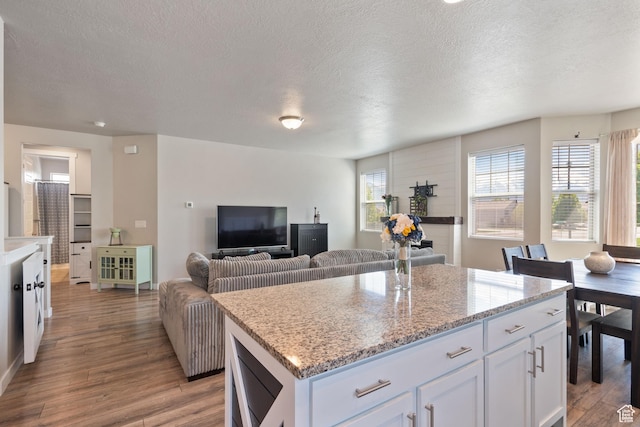 1013 W 90 S, Spanish Fork, UT 84660 - kitchen with light wood-type flooring, a textured ceiling, white cabinetry, a center island, and light stone countertops