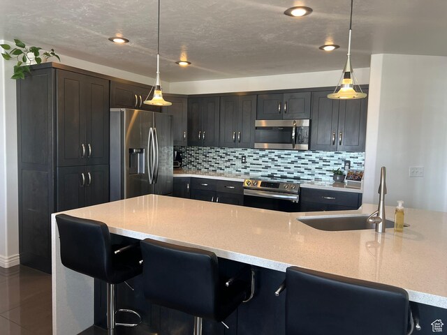 1307 E Brandy Ln S, Tooele, UT 84074 - kitchen with a sink, a kitchen bar, tasteful backsplash, light stone counters, and appliances with stainless steel finishes