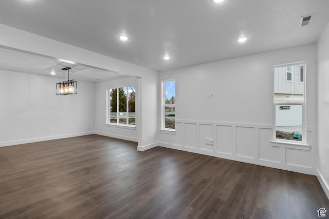 empty room featuring visible vents, baseboards, recessed lighting, dark wood finished floors, and a notable chandelier
