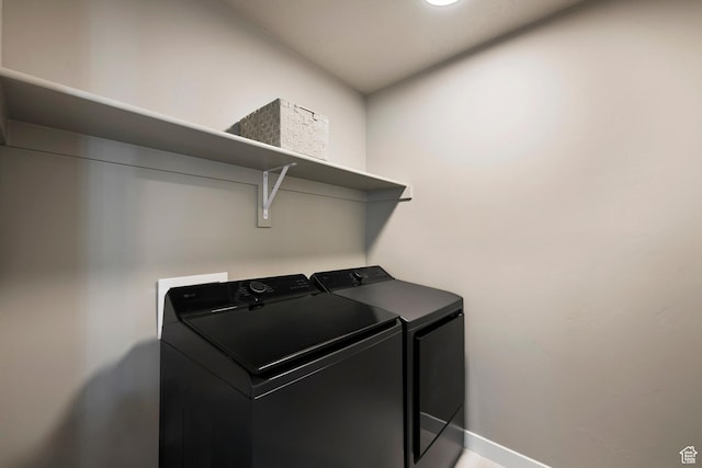 washroom with baseboards, washing machine and clothes dryer, and laundry area