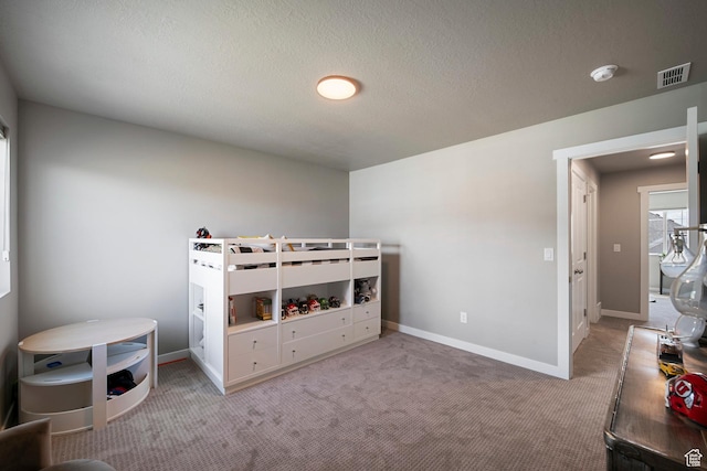 bedroom featuring a textured ceiling, visible vents, carpet, and baseboards