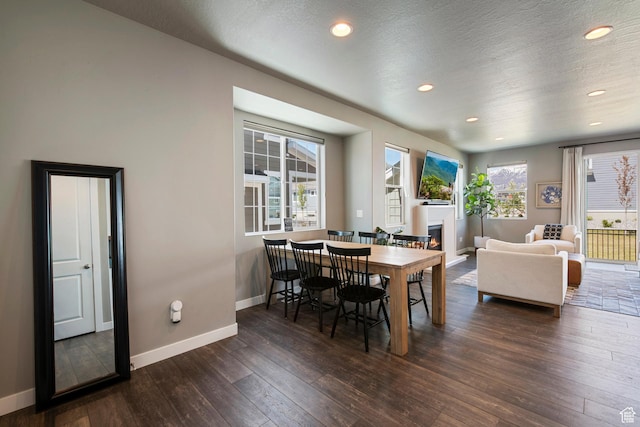 dining space featuring a glass covered fireplace, recessed lighting, baseboards, and dark wood finished floors