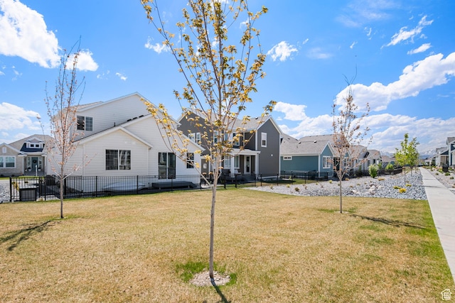 rear view of house with fence, a yard, and a residential view