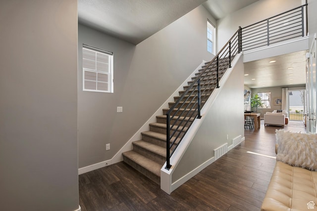 stairway with baseboards, visible vents, and wood finished floors